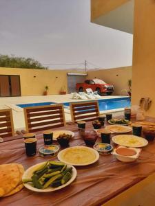 una mesa de madera con platos de comida. en شاليه سد الموجب, en Al Mara‘ah
