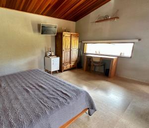 sypialnia z łóżkiem, biurkiem i oknem w obiekcie Chalé com borda infinita vista para represa w mieście Joanópolis