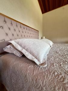 łóżko z białą narzutą i poduszkami w obiekcie Chalé com borda infinita vista para represa w mieście Joanópolis