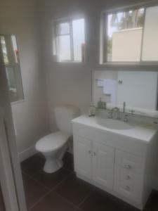 Baño blanco con aseo y lavamanos en FRANGIPANI HOUSE, en Gladstone
