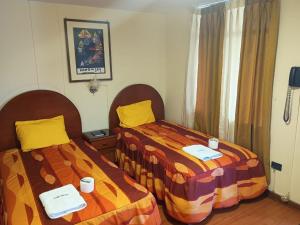 - deux lits assis l'un à côté de l'autre dans une pièce dans l'établissement Hostal Koricancha, à Sicuani