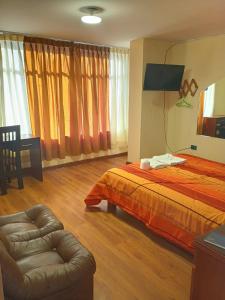 - une chambre avec un lit, une chaise et un canapé dans l'établissement Hostal Koricancha, à Sicuani