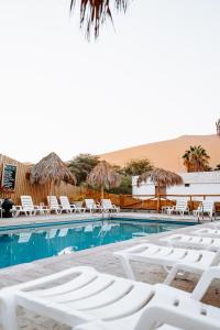 a swimming pool with white lounge chairs in the desert at Ecocamp Huacachina in Ica
