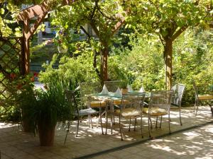 eine Terrasse mit einem Tisch und Stühlen unter Bäumen in der Unterkunft Hotel Oranien in Nastätten
