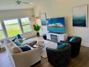a living room with couches and a flat screen tv at Brand New 5-Bedroom Lake Michigan Home + Hot Tub! in Ludington
