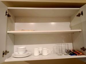 a shelf with cups and plates on it in a kitchen at Avida Tower 3 Unit 606 in Iloilo City +4 photos