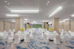 une salle de banquet avec des tables blanches et des chaises blanches dans l'établissement voco Lianyungang Haizhou Bay, an IHG Hotel, à Lianyungang