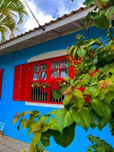 een rood raam op een blauw huis met rode bloemen bij Pequi hostel in Florianópolis