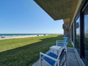 eine Veranda mit zwei blauen Stühlen und dem Strand in der Unterkunft Island House Condominiums Unit 113 in Padre Island