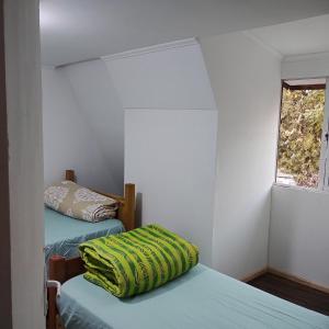 Habitación pequeña con 2 camas y ventana en Backpackers House - Near The Airport, en Santiago