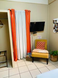 een woonkamer met een oranje gordijn en een stoel bij City Garden Apartment in Belize City