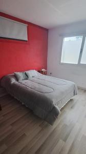 1 dormitorio con 1 cama grande y pared roja en CasaAcanti en Mar del Plata