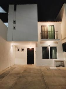 a white building with a black door and a balcony at Casa Real San Marcos B en Privada Zona Norte in Irapuato