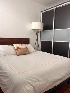 a white bed with a pillow and a lamp at Condesa Residence Amsterdam E Cozy Living Space in the Heart of the City on Amsterdam Avenue in Mexico City