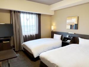 a hotel room with two beds and a flat screen tv at Hotel Route Inn Isehara Ooyama Inter -Kokudo 246 Gou- in Isehara