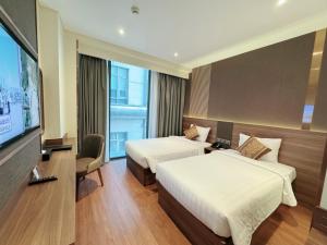 a hotel room with two beds and a flat screen tv at Northern Charm Hotel in Ho Chi Minh City
