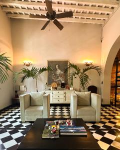 a living room with two chairs and a ceiling fan at Casa Charlotte - Alma Hotels in Santa Marta