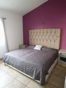 - une chambre avec un grand lit et un mur pourpre dans l'établissement Casa Minimalista Bosques- 3 pisos, à Oaxtepec 16 autres photos