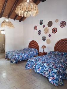 1 dormitorio con 3 camas y lámpara de araña en Hotel Cabañas Chalamu, en Pátzcuaro