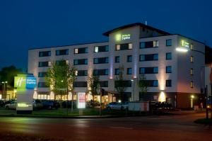 a large building with lights on it at night at Holiday Inn Express Cologne Mülheim, an IHG Hotel in Cologne
