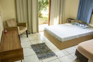 a bedroom with a bed and a chair and a window at Hostel Rio do Boi in Praia Grande