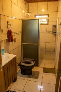 a bathroom with a shower with a toilet and a sink at Hostel Rio do Boi in Praia Grande