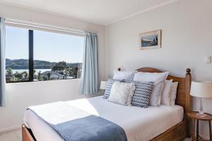a bedroom with a bed with a large window at Harbourside Cove in Raglan