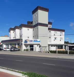 un edificio blanco al lado de una calle en Capão Praia Hotel, en Capão da Canoa