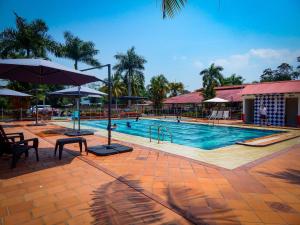 a swimming pool with chairs and umbrellas in a resort at Hotel campestre las palmas in Villavicencio +45 photos