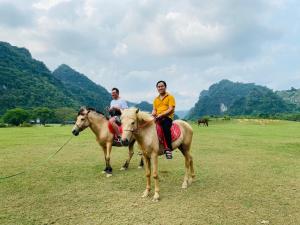deux personnes à cheval dans un champ dans l'établissement Homestay Rung Xanh Huu Lien, à Làng Ben