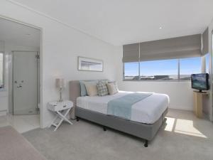 a white bedroom with a bed and a television at Luxury Apartments at Bells Blvd in Kingscliff