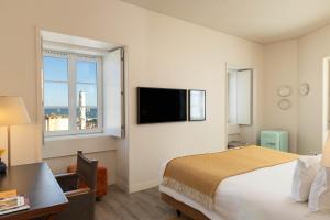 a hotel room with a bed and a desk and a television at Memmo Alfama - Design Hotels in Lisbon