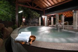 einen Whirlpool mit einem Stuhl und einem Tisch in der Unterkunft Hoya Hot Springs Resort, Guanziling in Stadtteil Baihe District