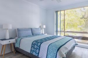 a white bedroom with a bed and a window at Waterfront on Plover in Sussex inlet