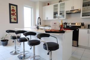 une cuisine avec des tabourets de bar noirs à un comptoir dans l'établissement Brand new luxurious home, located in Lindsay., à Kawartha Lakes