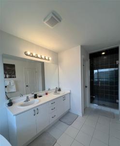 La salle de bains est pourvue de 2 lavabos et d'un grand miroir. dans l'établissement Brand new luxurious home, located in Lindsay., à Kawartha Lakes