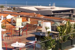 einen Balkon mit Tischen, Stühlen und Meerblick in der Unterkunft Memmo Alfama - Design Hotels in Lissabon
