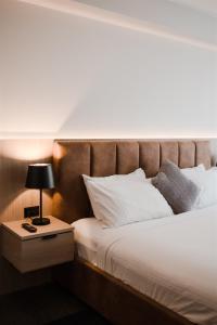 a bed with a brown headboard and a table with a lamp at Pasadena Sydney in Church Point