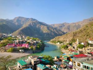 a view of a river with buildings and mountains at Trinetra Guest House in Rishīkesh