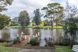 a park with a lake and a wooden dock at Waterfront on Plover in Sussex inlet