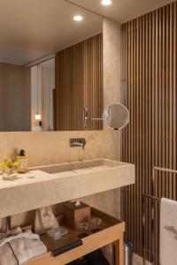 La salle de bains est pourvue d'un lavabo et d'un grand miroir. dans l'établissement Memmo Príncipe Real - Design Hotels, à Lisbonne