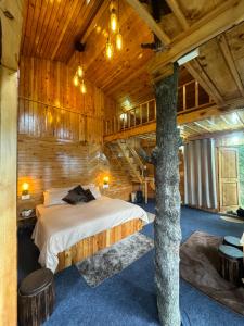 un dormitorio con una cama y un árbol dentro en Kakapo Nest By Woodoo Treehouse and Cottages, en Jibhi