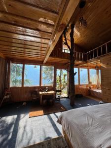 1 dormitorio con cama, mesa y ventanas en Kakapo Nest By Woodoo Treehouse and Cottages, en Jibhi