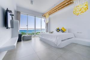 a white bedroom with a bed and a view of the ocean at Cat at Greece in Nanwan