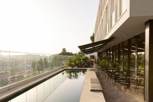 a building with a swimming pool and tables and chairs at Memmo Príncipe Real - Design Hotels in Lisbon