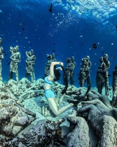 a mermaid sitting on the rocks with a group of divers at Saellahouse in Gili Trawangan
