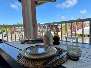 a table with plates and wine glasses on a balcony at Bahia Beach- Duplex, plage privée, Netflix in Cayenne +11 photos