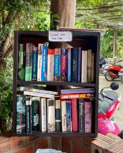 uma estante cheia de livros com um cartaz que lê tem um a menos em Sunrise Riverside Pool Hostel em Luang Prabang