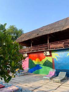 un mural en el lateral de un edificio con sillas en Sunrise Riverside Pool Hostel, en Luang Prabang
