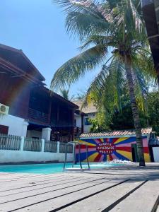 uma palmeira ao lado de uma piscina com uma placa em Sunrise Riverside Pool Hostel em Luang Prabang